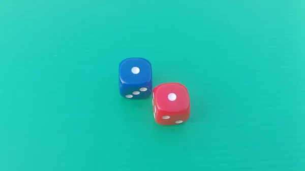 Pair of colorful dice placed on a bright green background.