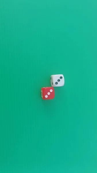 Pair of colorful dice placed on a bright green background.