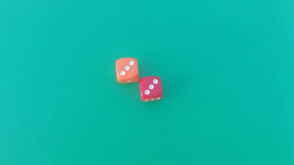 Pair of colorful dice placed on a bright green background.