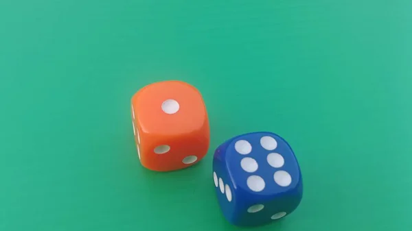 Pair of colorful dice placed on a bright green background.