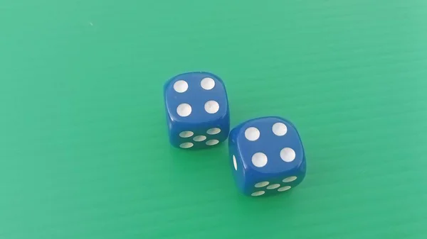 Pair of colorful dice placed on a bright green background.