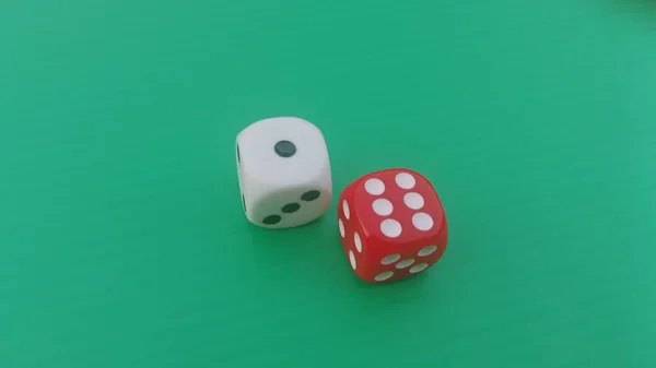 Pair of colorful dice placed on a bright green background.