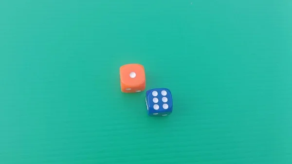 Pair of colorful dice placed on a bright green background.