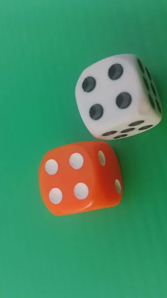 Pair of colorful dice placed on a bright green background.