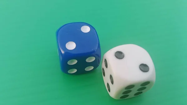 Pair of colorful dice placed on a bright green background.