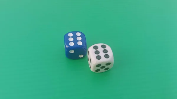 Pair of colorful dice placed on a bright green background.
