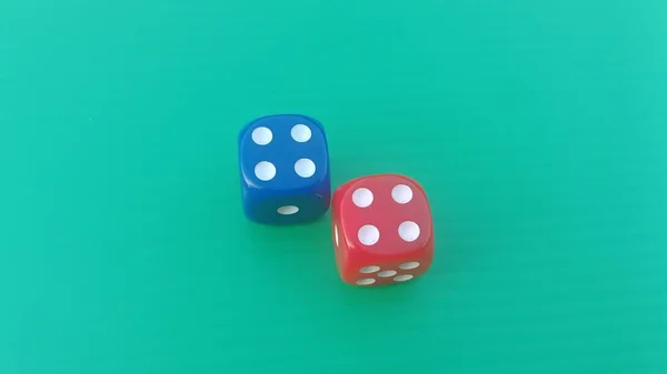 Pair of colorful dice placed on a bright green background.