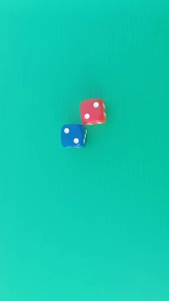 Pair of colorful dice placed on a bright green background.