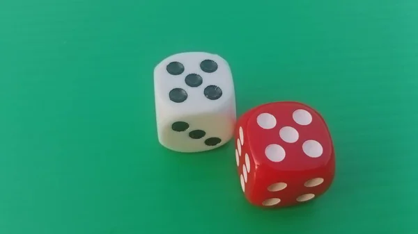 Pair of colorful dice placed on a bright green background.