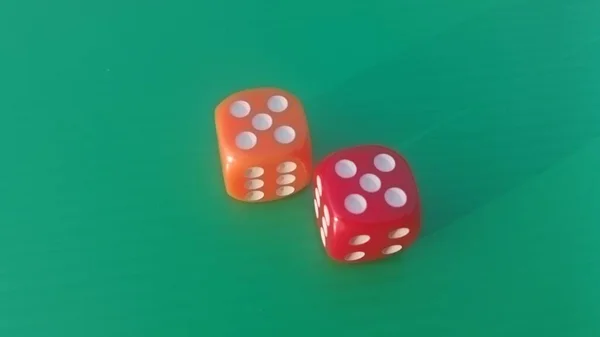 Pair of colorful dice placed on a bright green background.