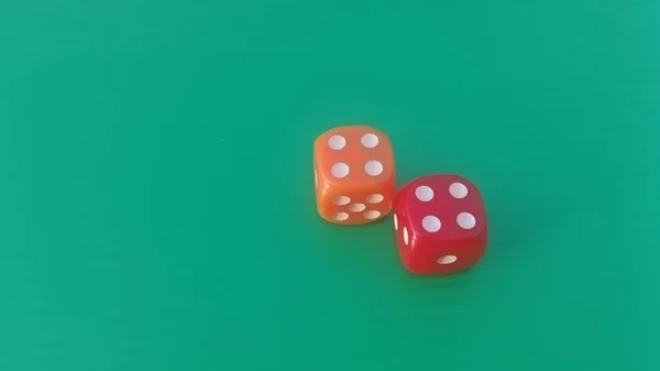 Pair of colorful dice placed on a bright green background.