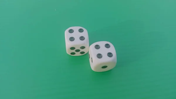 Pair of colorful dice placed on a bright green background.