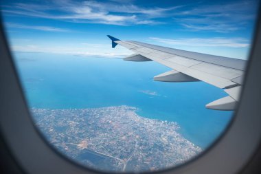 Güzel mavi gökyüzü ve bulut arka planında uçak kanadı. Pattaya Tayland denizi üzerindeki uçuş sırasında irtifa olarak. Pencereden bakan bir uçağın kanadı.