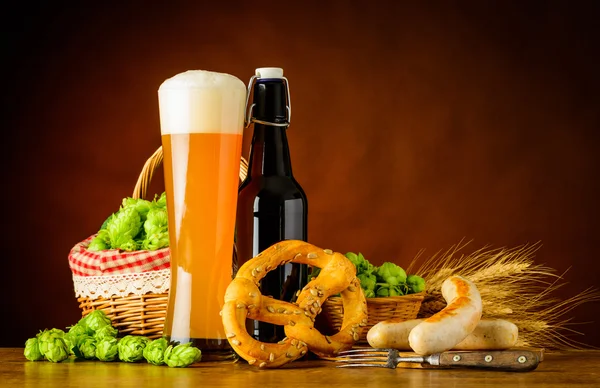 Sklo a láhev pšeničné pivo s Prezel a klobásy — Stock fotografie