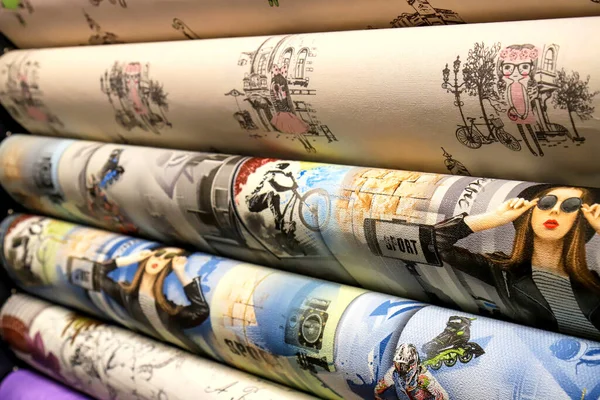 Rolled up rolls of vinyl wallpaper in a building supermarket, shop. Colorful wallpaper for the wall, decorative finishing materials for the renovation of a room, interior