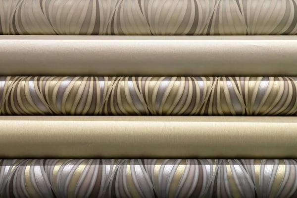 Rolled up rolls of vinyl wallpaper. Different textures and colors, as background. Beige, gray wallpapers with abstract patterns for the wall. Decorative materials for renovation of room, interior