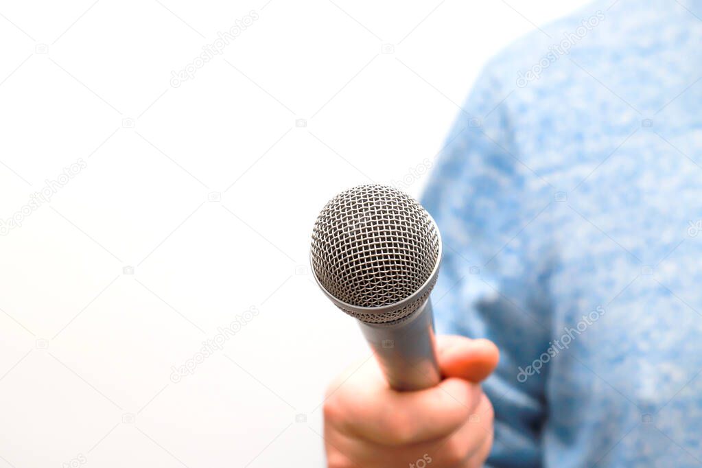 A man holds a silver, gray microphone in his hand and conducts business interviews, journalistic reporting, public speaking, press conference, sings karaoke
