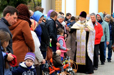 Kilise kıyafetli Ortodoks rahibi, Paskalya 'da kilisenin yakınındaki kilise cemaatine serpiyor. Dini ayin, vaftiz töreni, Hıristiyan katedrali. Dnipro şehri, Dnepropetrovsk, Ukrayna, 16 04 2019