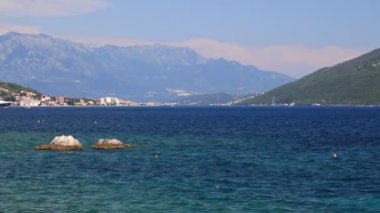 Karadağ 'ın Herceg Novi kentindeki ekolojik açıdan temiz yaz plajlarında, yüksek ve güzel dağların yakınlarındaki şeffaf berrak sular sıçradı. Karadağ 'da Kotor Körfezi, Akdeniz' de dinlenme, seyahat ve turizm.
