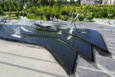 Parkta, yüksek binaların ve gökdelenlerin arka planında dans eden fıskiyeler. Dnipro, Dnepropetrovsk, Ukrayna 'da bahar, yaz caddesi. Drone görünümü, şehir manzarası