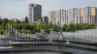 Güzel bir parkta, yüksek binaların ve gökdelenlerin karşısında dans eden bir çeşme var. Dnepr, Dnipropetrovsk, Ukrayna 'da bahar, yaz caddesi. Drone görünümü, şehir manzarası