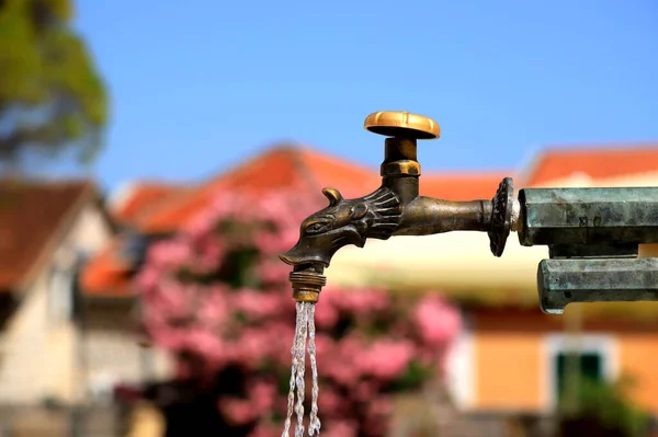 Antique water tap at fountain in the old town of Herceg Novi, Montenegro. Water flows from a beautiful bronze tap, Belavista Square in Montenegro. Vintage plumbing, pipes for the house