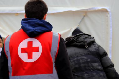 Dnipro Ukrayna, 01-15 2023. Kızıl Haç gönüllüleri, Rus roket saldırısından sonra yıkılmış evin yakınındaki yaralı insanlara yardım etmek için insani yardım dağıtıyor. Sağlık görevlisi üniformasında Kızıl Haç işareti. Ukrayna 'daki savaş.