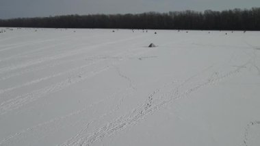 Kışın buzlu arka plan. Balıkçılar güzel mavi buzda, donmuş nehirde, kışın gölde, tepedeki drone manzarasında balık avlıyorlar..