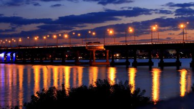 Akşam, su üzerinde ışıklar yansıyan köprü
