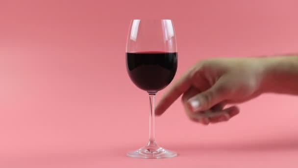 El hombre bebe vino tinto. Configuración del estudio sobre un fondo rosa — Vídeos de Stock