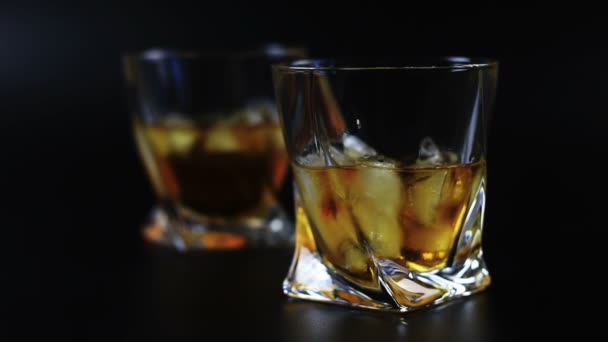 Whisky som hälls i ett glas mot svart bakgrund — Stockvideo