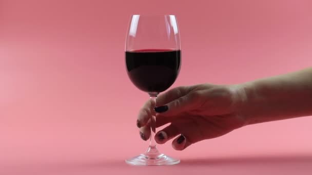 Жінка п'є червоне вино. Налаштування студії на рожевому фоні — стокове відео