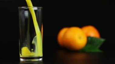Portakal suyu bir bardak siyah bir arka plan içine dökülen adam