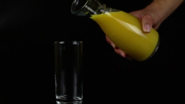 Homme verser du jus d'orange dans un verre sur un fond noir — Video