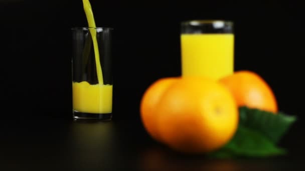 Uomo versando succo d'arancia in un bicchiere su uno sfondo nero — Video Stock