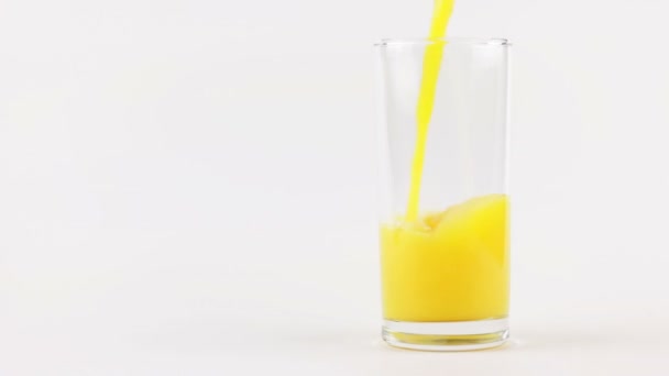 Homme verser du jus d'orange dans un verre sur un fond blanc — Video