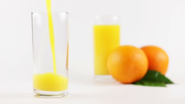 Homme verser du jus d'orange dans un verre sur un fond blanc — Video