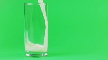 Süt bir cam içine yeşil bir arka plan üzerine dökülür.