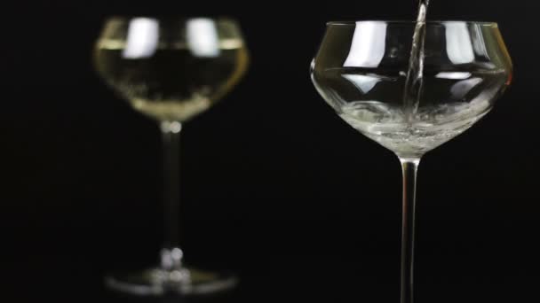 Champagne wordt gegoten in een glas op een zwarte achtergrond — Stockvideo