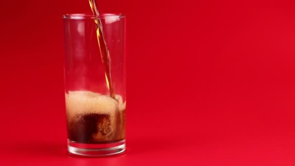 Cola giet in glas op een rode achtergrond — Stockvideo
