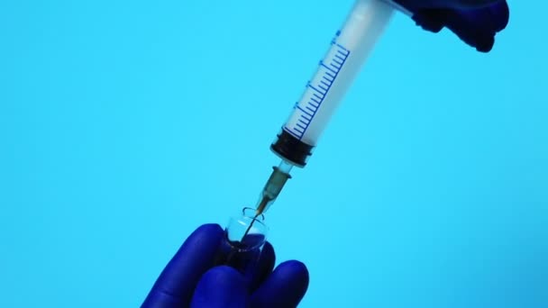 Médecin en gants bleus cueillant un médicament dans la seringue 