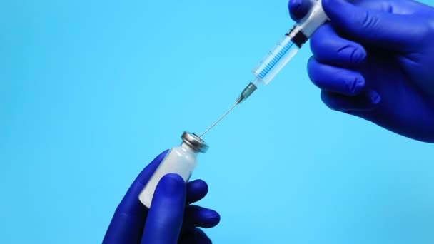 Médecin en gants bleus cueillant un médicament dans la seringue — Video