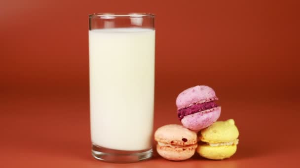 Vaso de leche y macarrón sobre fondo marrón — Vídeo de stock