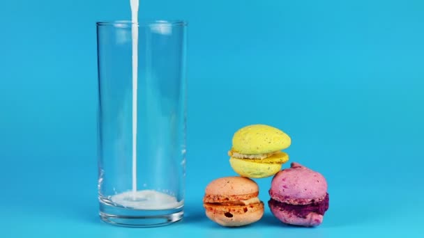 Vaso de leche y macarrón sobre fondo azul — Vídeos de Stock