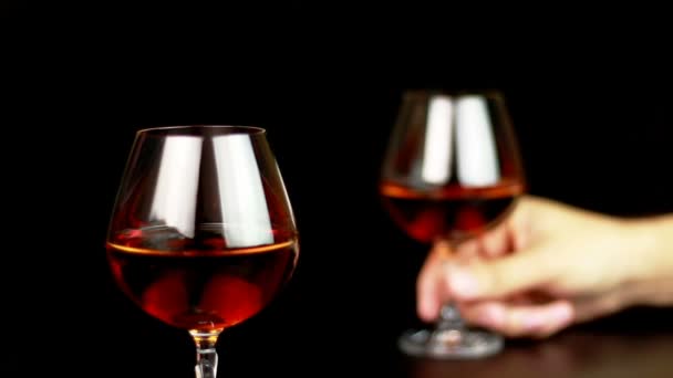 Man neemt een glas met brandy op zwarte achtergrond — Stockvideo