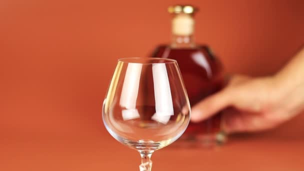 Cognac. Hälla konjak från en flaska till ett glas över brun bakgrund — Stockvideo