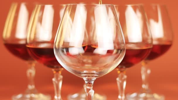 Close up of brandy being poured into snifter on brown background — Stock Video