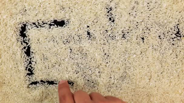 Mannen hand trekt woord eten op het oppervlak van rijst — Stockvideo