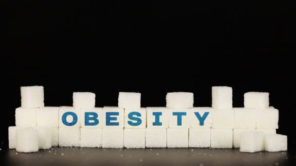 Mans mão coloca cubos de açúcar em que é inscriçãoa palavra obesidade — Vídeo de Stock