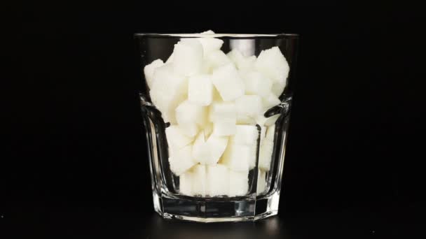 Glass filled with white sugar cubes symbolizing the high content of sugar in our drinks and diet. — Stock Video